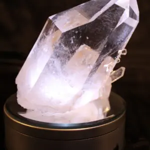 A clear quartz crystal glowing softly on a black base.