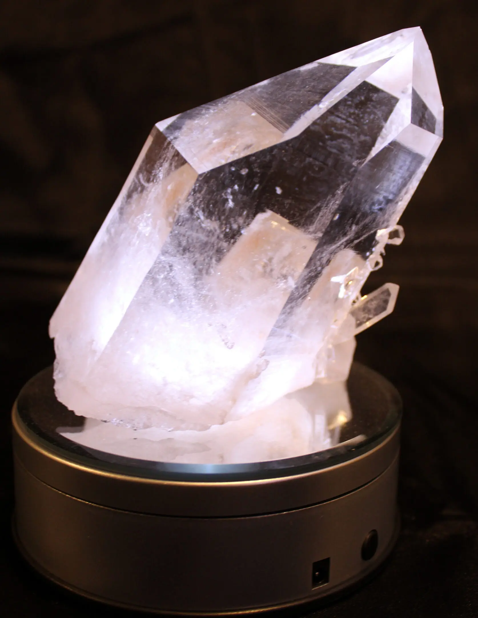A clear quartz crystal glowing softly on a black base.