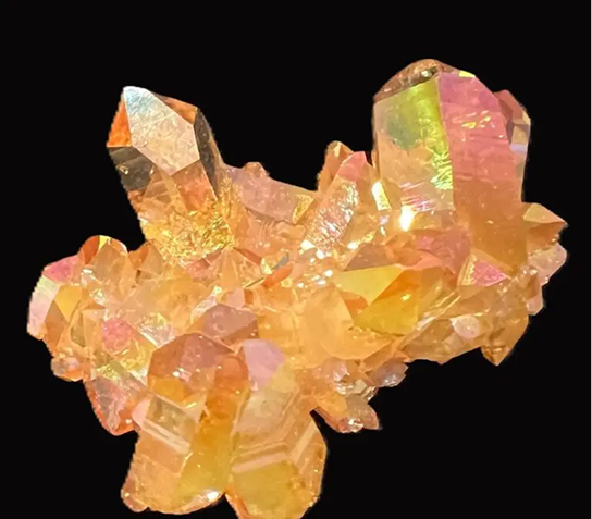 Cluster of golden-orange crystals with iridescent sheen on black background.