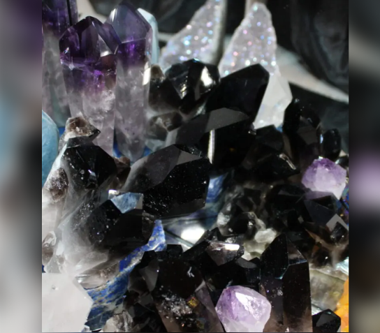 Close-up of dark amethyst crystals with purple tips sparkling under light.