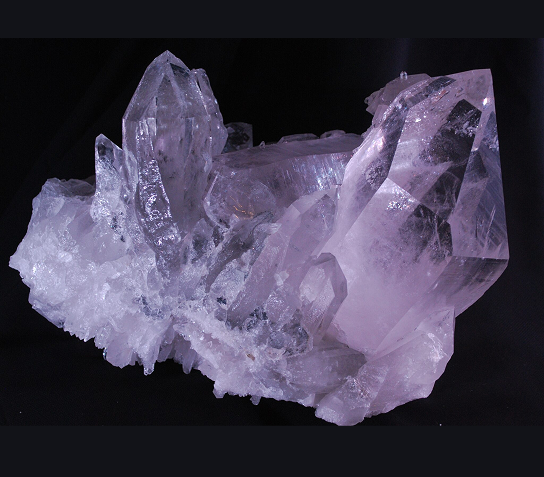 Close-up of a cluster of purple amethyst crystals on a dark background.