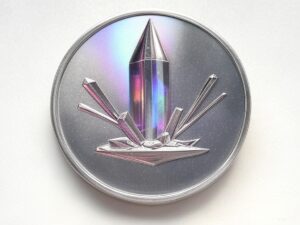 A silver coin with a crystal on it