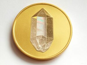 A gold coin with an image of a crystal on it.